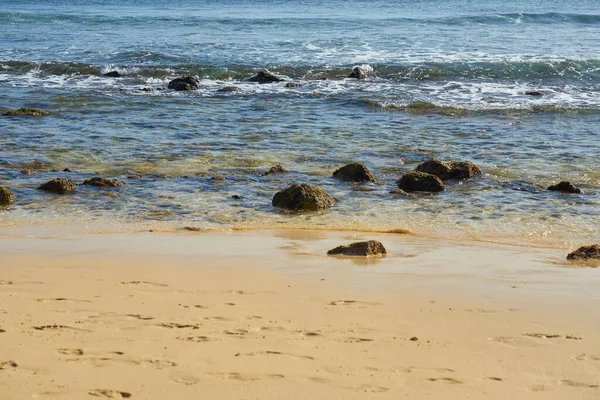 Rocks and waves on a sandy tropical beach