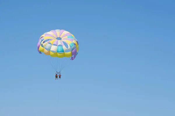 Colorful parasailing parachute against a clear blue sky