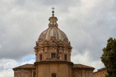 Bulutlu bir gökyüzünün arka planında antik bir Roma binasının kubbesi.