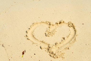 Tropik bir plajın kumlarına çizilmiş bir kalp.