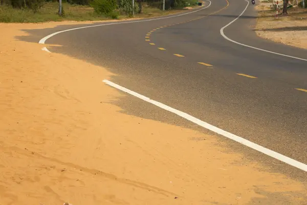 Desert sand steps on an asphalt road