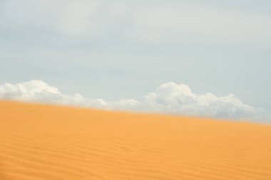 Çölde kum tepeciği, arkasında bulutlar.