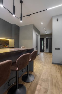 Modern luxury apartment with a free layout in a loft style in gray and dark colors. Stylish kitchen area with an island and marble countertop