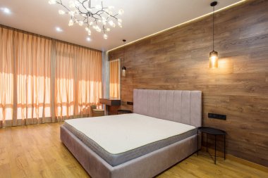 Büyük, modern yatak odası. Yatak başlıklı ahşap kaplamalı duvarlar