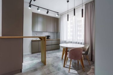 Pencere kenarındaki yemek pişirme alanında bir sürü dolap, tezgah, lavabo, mutfak aletleri mermer bir duvarın yanında..