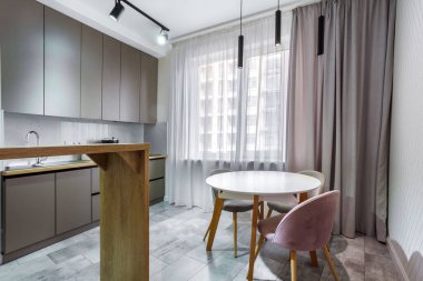 Pencere kenarındaki yemek pişirme alanında bir sürü dolap, tezgah, lavabo, mutfak aletleri mermer bir duvarın yanında..