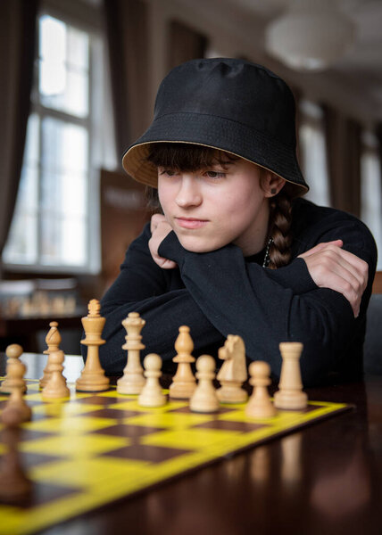 The girl plays chess. Pieces on the chessboard. Chess game, close-up, portrait. Chess tournament, competition