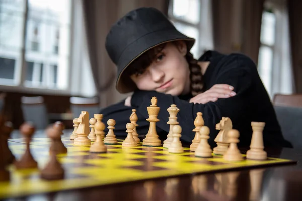 The girl plays chess. Pieces on the chessboard. Chess game, close-up, portrait. Chess tournament, competition