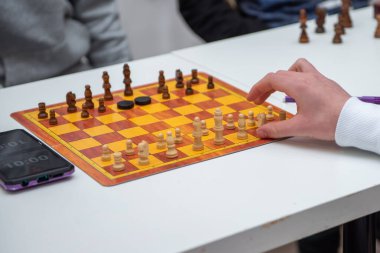 Chess player holding a piece and playing chess on a chessboard in the background, game tournament concept