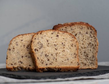 Tohumlu çavdar ekmeği açık bir masada, karanlık bir tahtanın üzerinde yatıyor. Ev pastanem. Organik tam tahıllı ekmek. Bio Dinkel Brot. Sağlıklı ekmek. Karbonhidratlar. Sağlıklı beslenme. Sağlıklı kahvaltı..