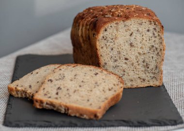 Tohumlu çavdar ekmeği açık bir masada, karanlık bir tahtanın üzerinde yatıyor. Ev pastanem. Organik tam tahıllı ekmek. Bio Dinkel Brot. Sağlıklı ekmek. Karbonhidratlar. Sağlıklı beslenme. Sağlıklı kahvaltı..