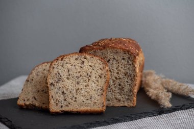 Tohumlu çavdar ekmeği açık bir masada, karanlık bir tahtanın üzerinde yatıyor. Ev pastanem. Organik tam tahıllı ekmek. Bio Dinkel Brot. Sağlıklı ekmek. Karbonhidratlar. Sağlıklı beslenme. Sağlıklı kahvaltı..