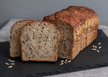 Tohumlu çavdar ekmeği açık bir masada, karanlık bir tahtanın üzerinde yatıyor. Ev pastanem. Organik tam tahıllı ekmek. Bio Dinkel Brot. Sağlıklı ekmek. Karbonhidratlar. Sağlıklı beslenme. Sağlıklı kahvaltı..