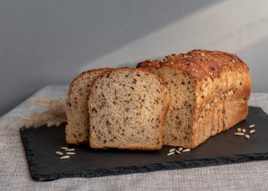 Tohumlu çavdar ekmeği açık bir masada, karanlık bir tahtanın üzerinde yatıyor. Ev pastanem. Organik tam tahıllı ekmek. Bio Dinkel Brot. Sağlıklı ekmek. Karbonhidratlar. Sağlıklı beslenme. Sağlıklı kahvaltı..