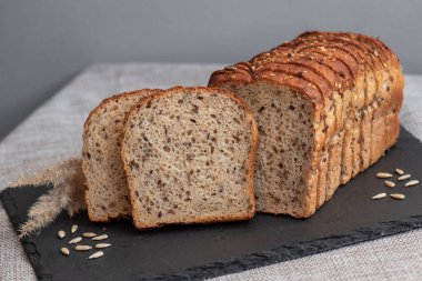 Tohumlu çavdar ekmeği açık bir masada, karanlık bir tahtanın üzerinde yatıyor. Ev pastanem. Organik tam tahıllı ekmek. Bio Dinkel Brot. Sağlıklı ekmek. Karbonhidratlar. Sağlıklı beslenme. Sağlıklı kahvaltı..
