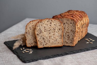 Tohumlu çavdar ekmeği açık bir masada, karanlık bir tahtanın üzerinde yatıyor. Ev pastanem. Organik tam tahıllı ekmek. Bio Dinkel Brot. Sağlıklı ekmek. Karbonhidratlar. Sağlıklı beslenme. Sağlıklı kahvaltı..