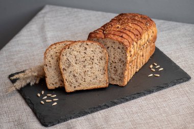 Tohumlu çavdar ekmeği açık bir masada, karanlık bir tahtanın üzerinde yatıyor. Ev pastanem. Organik tam tahıllı ekmek. Bio Dinkel Brot. Sağlıklı ekmek. Karbonhidratlar. Sağlıklı beslenme. Sağlıklı kahvaltı..
