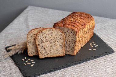 Tohumlu çavdar ekmeği açık bir masada, karanlık bir tahtanın üzerinde yatıyor. Ev pastanem. Organik tam tahıllı ekmek. Bio Dinkel Brot. Sağlıklı ekmek. Karbonhidratlar. Sağlıklı beslenme. Sağlıklı kahvaltı..