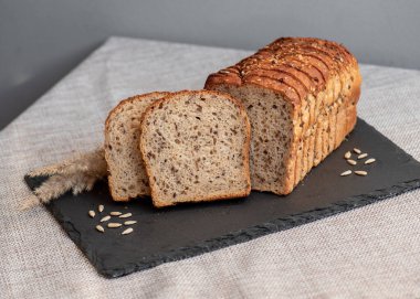 Tohumlu çavdar ekmeği açık bir masada, karanlık bir tahtanın üzerinde yatıyor. Ev pastanem. Organik tam tahıllı ekmek. Bio Dinkel Brot. Sağlıklı ekmek. Karbonhidratlar. Sağlıklı beslenme. Sağlıklı kahvaltı..