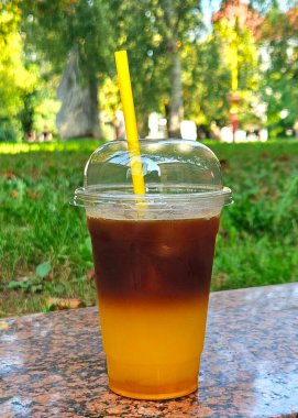 Bir bardak buzlu soğuk içecek. Açık bir kafede portakal suyu ile kahve. Yaz içkileri. Plastik bardakta soğuk içecek.