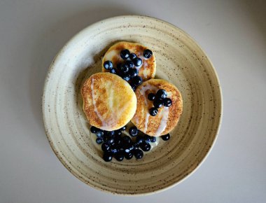Tabağında yaban mersini olan peynirli kekler. Sağlıklı kahvaltı. yakın plan