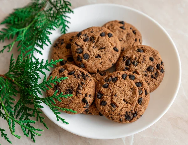 Chocolate cookies on a plate with spruce branches on the table. Dark chocolate cookies on a plate, Christmas cookies chocolate cinnamon sweet dessert holiday treat new year and christmas food