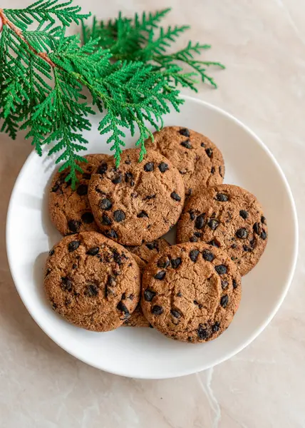 Chocolate cookies on a plate with spruce branches on the table. Dark chocolate cookies on a plate, Christmas cookies chocolate cinnamon sweet dessert holiday treat new year and christmas food
