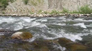 Bir dağ nehrinin hareketi, kayaların arasından akan bir akarsu. Nehir taşlarına akan suyla yakın çekim, bir dağ nehrinde akan temiz su. Nehirde akan su