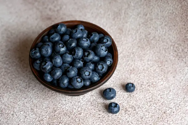 Tahta bir masada, ahşap bir kasede taze yaban mersini. Yaban mersinleri çeşitli vitaminler, mineraller ve diyet lifleri açısından zengindir. Bu da onları dünyadaki en iyi 10 süper yiyecekten biri yapar: yaban mersini ve yaban mersini.