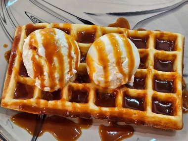 Karamelli Belçika waffle 'ına iki kepçe vanilyalı dondurma. Lezzetli waffle ve karamelli dondurma.