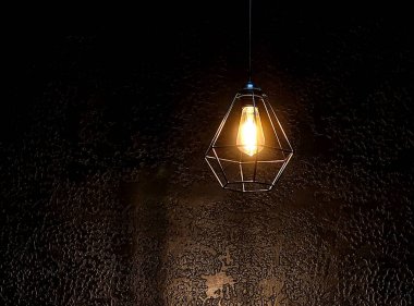 Dekoratif antika Edison tarzı ampuller. Gri bir duvarın arka planında parlak ipliklerle parlayan parlak, yuvarlak, güzel bir retro lamba, yakın plan. Tavanda asılı duran eski tozlu ampul karanlıkta büyüyor.