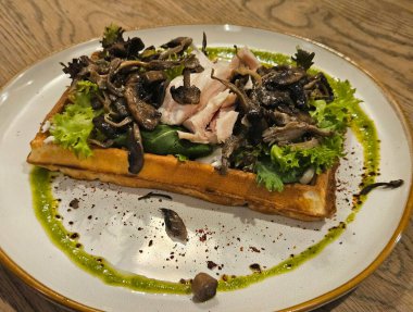 Mantarlı Belçika waffle 'ı, sous vide tavuğu ve marul. Güzel bir restoran sunumu. Yakın plan.