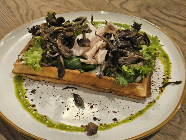 Belgian waffle with mushrooms, sous vide chicken and lettuce. Beautiful restaurant presentation. Close-up