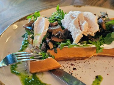 Soslu tavuk, kızarmış mantar ve otlu Belçika waffleları, yakın plan lezzetli yiyecekler.