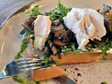 Soslu tavuk, kızarmış mantar ve otlu Belçika waffleları, yakın plan lezzetli yiyecekler.