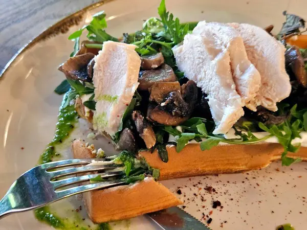 Soslu tavuk, kızarmış mantar ve otlu Belçika waffleları, yakın plan lezzetli yiyecekler.