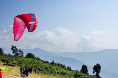 Renkli yamaç paraşütleri gökyüzünde huzur içinde süzülüyor, nefes kesen bir dağ ve bulutlarla dolu bir arka plan, özgürlük ve macera hissi veriyor..