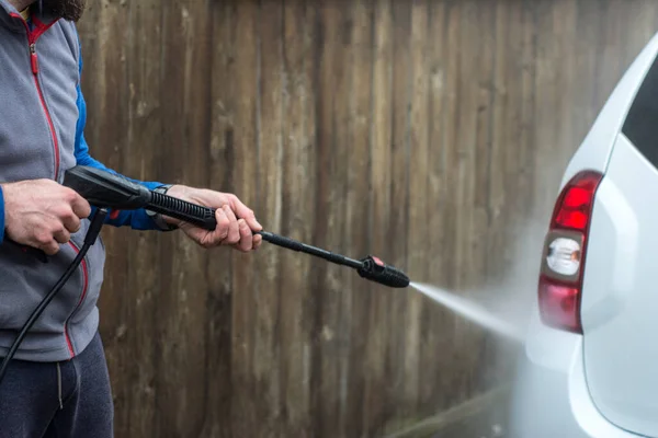 一个男人用手用一个大水头从一个弓箭手手中冲刷他的车的近照 清洗和消毒 期间的安保措施M — 图库照片