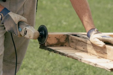 Öğütücüyle ahşap kapıları zımparalamak boyamadan önce kapıları temizlemek.