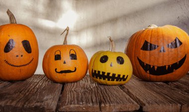 Gri arkaplanda ürkütücü suratlar çizilmiş balkabakları. Cadılar Bayramı