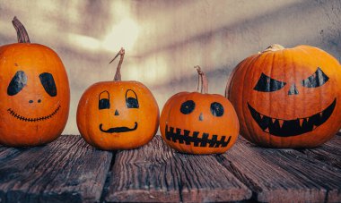 Gri arkaplanda ürkütücü suratlar çizilmiş balkabakları. Cadılar Bayramı