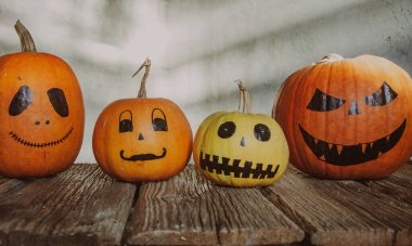 Gri arkaplanda ürkütücü suratlar çizilmiş balkabakları. Cadılar Bayramı