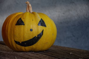 Gri arkaplanda ürkütücü suratlar çizilmiş balkabakları. Cadılar Bayramı