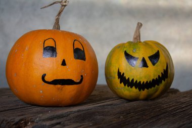 Gri arkaplanda ürkütücü suratlar çizilmiş balkabakları. Cadılar Bayramı