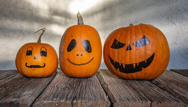 Pumpkins with drawn spooky faces on grey background. Halloween celebration