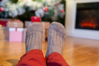 Ayaklar yün çoraplarda ve şömine arka planda Noel süslemeleri ile