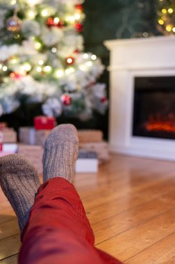 Ayaklar yün çoraplarda ve şömine arka planda Noel süslemeleri ile