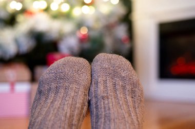 Ayaklar yün çoraplarda ve şömine arka planda Noel süslemeleri ile