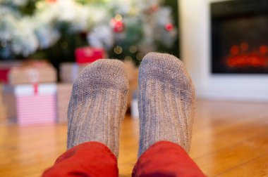 Ayaklar yün çoraplarda ve şömine arka planda Noel süslemeleri ile