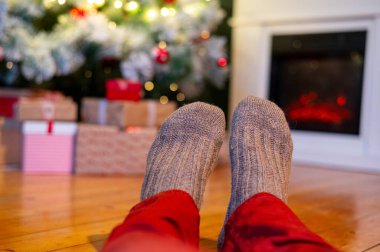 Ayaklar yün çoraplarda ve şömine arka planda Noel süslemeleri ile